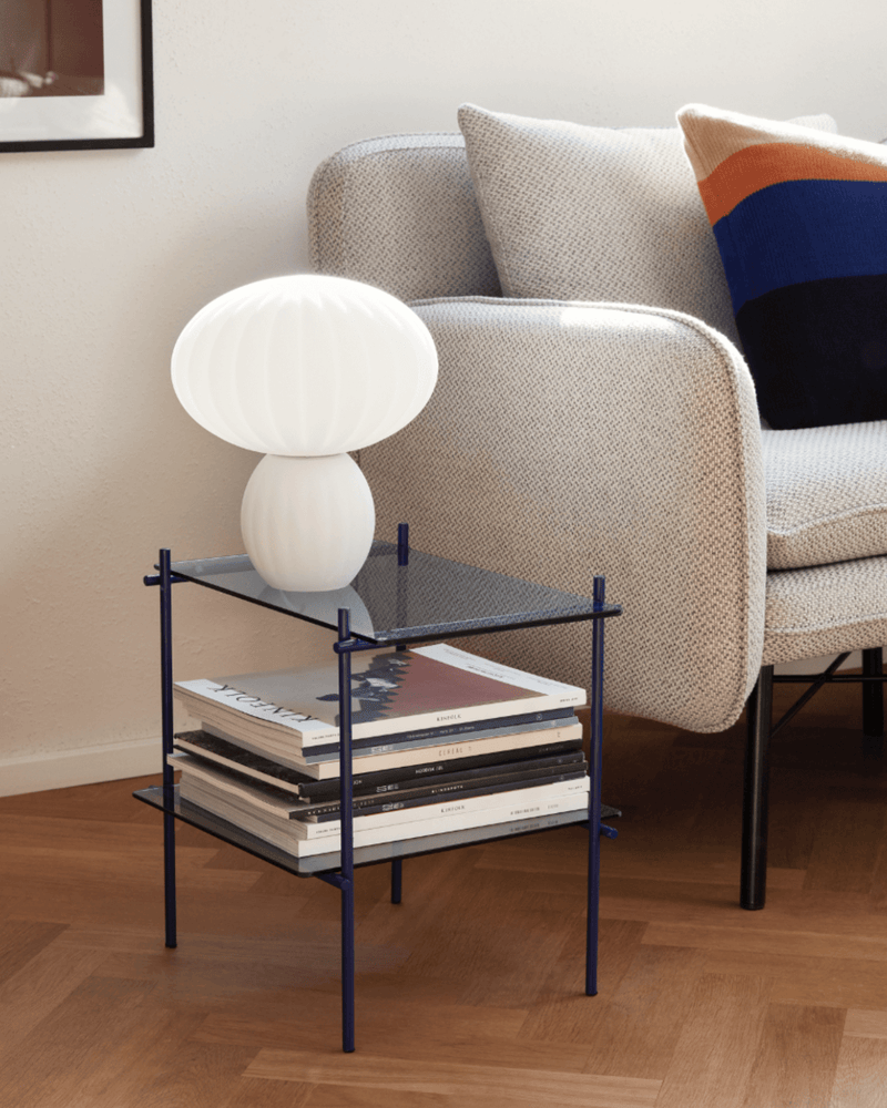 Hvid Kumu bordlampe fra Hübsch på lille sidebord ved sofa.