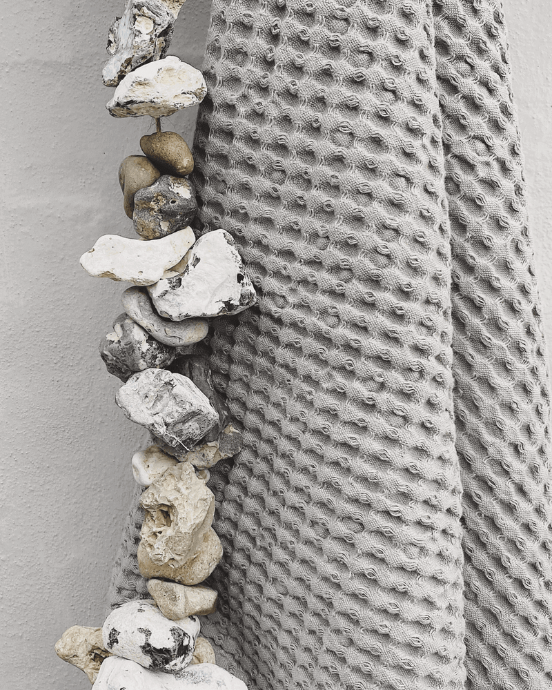 Close up af hullede sten fra stranden og  gråt håndklæde fra Humdakin