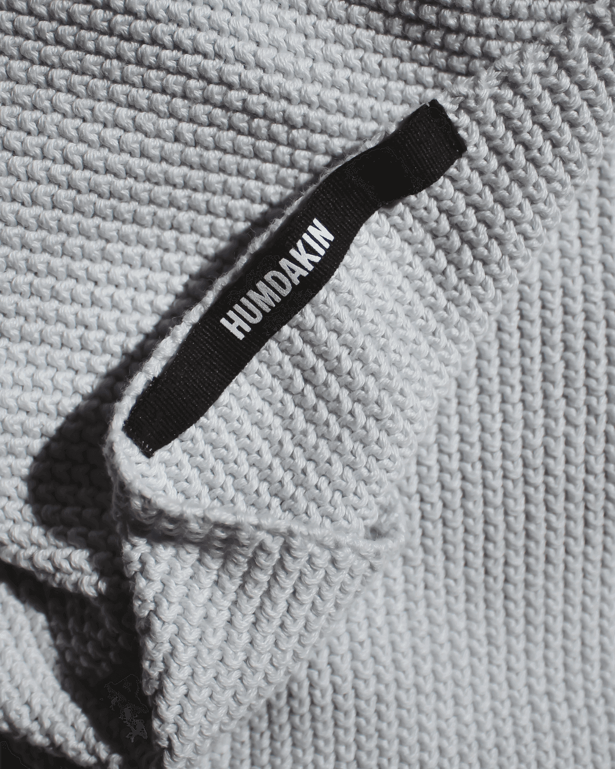 Detalje af strikket køkkenhåndklæde i blue glass med label.