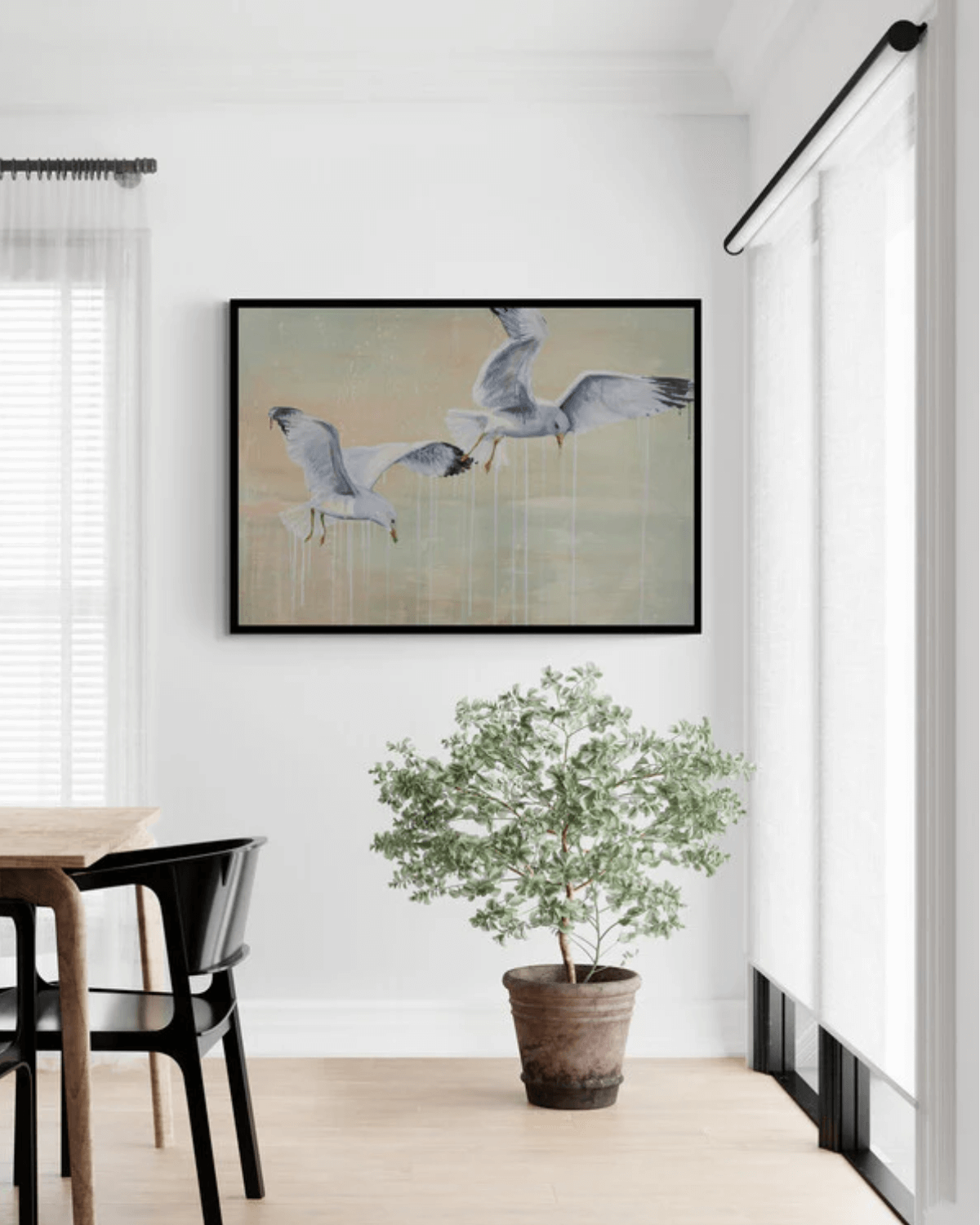 Spisestue med kunsttryk på væggen af to malede måger der kigger ned i vandet.