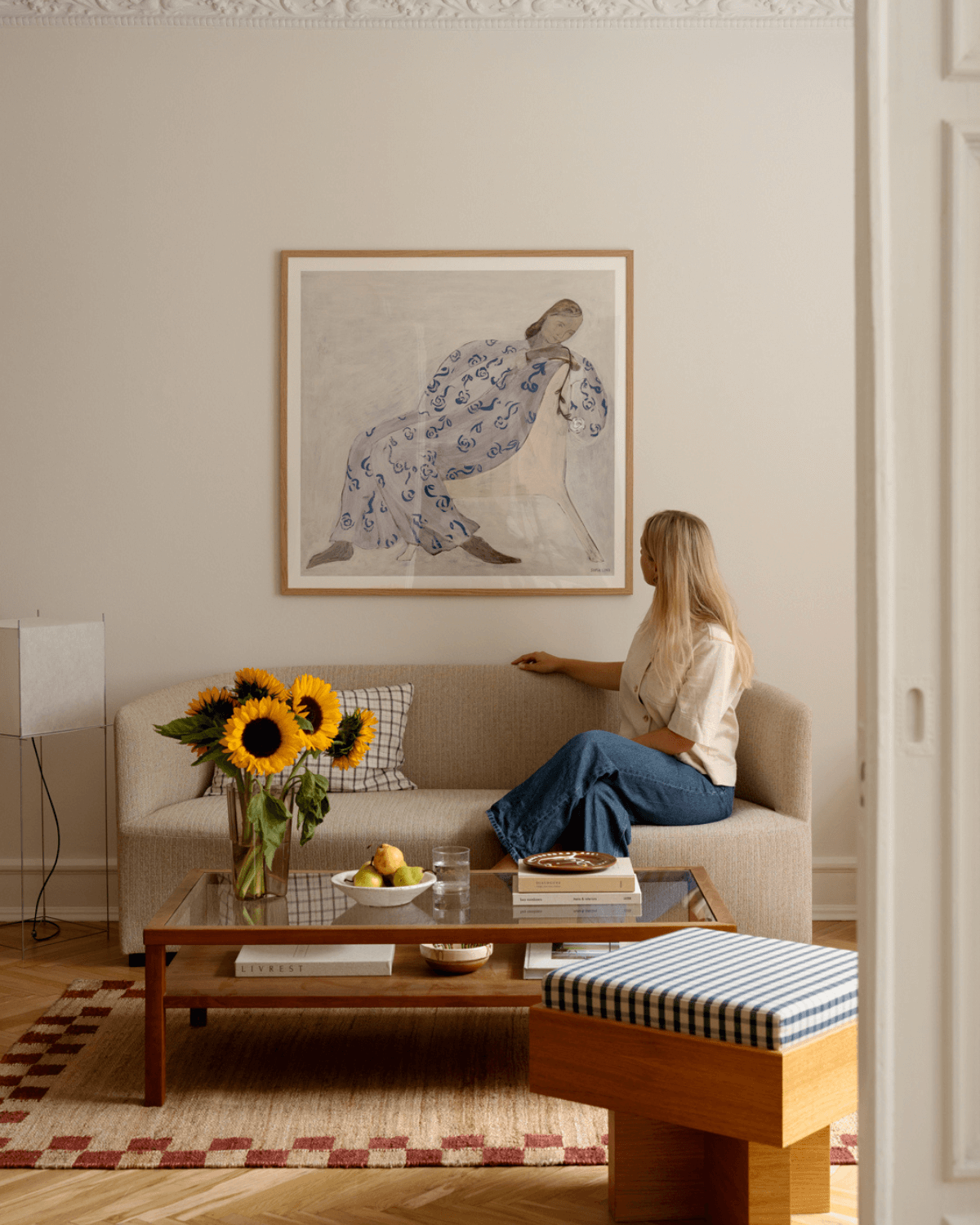 Kunsttryk med hvilende kvinde i hvid kjole med blåt mønster i ramme på væg i et roligt og stilfuldt hjem. 