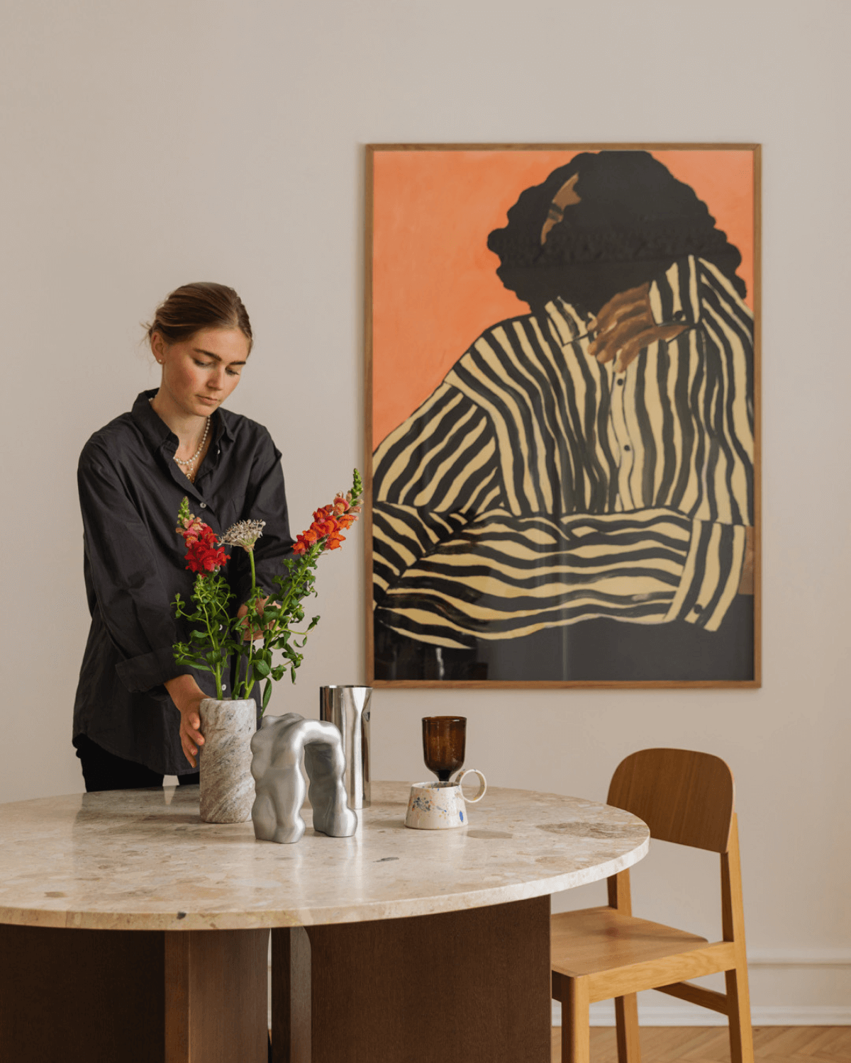 Indrammet kunsttryk af kvinde i stribet skjorte på væg i spisestue.