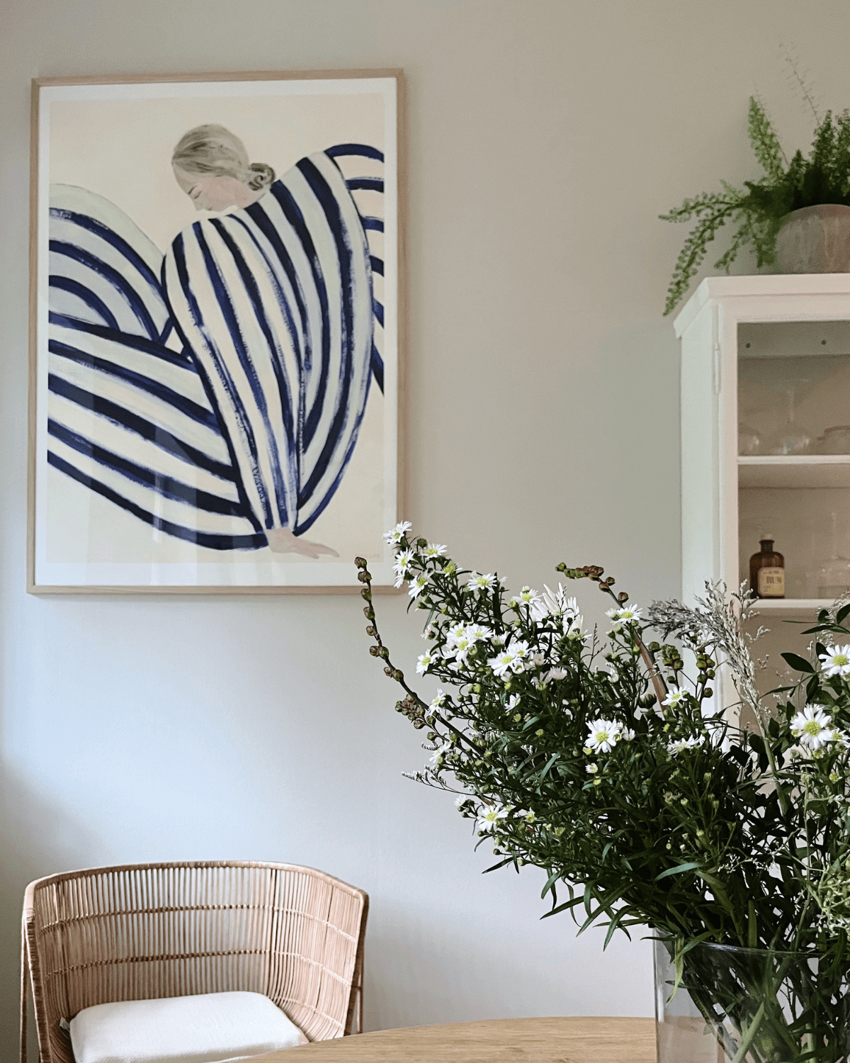 Plakat fra the poster club med kvinde i striber af Sofia Lind indrammet og ophængt i smukt rum. Giver personlighed til det minimalistiske hjem. 
