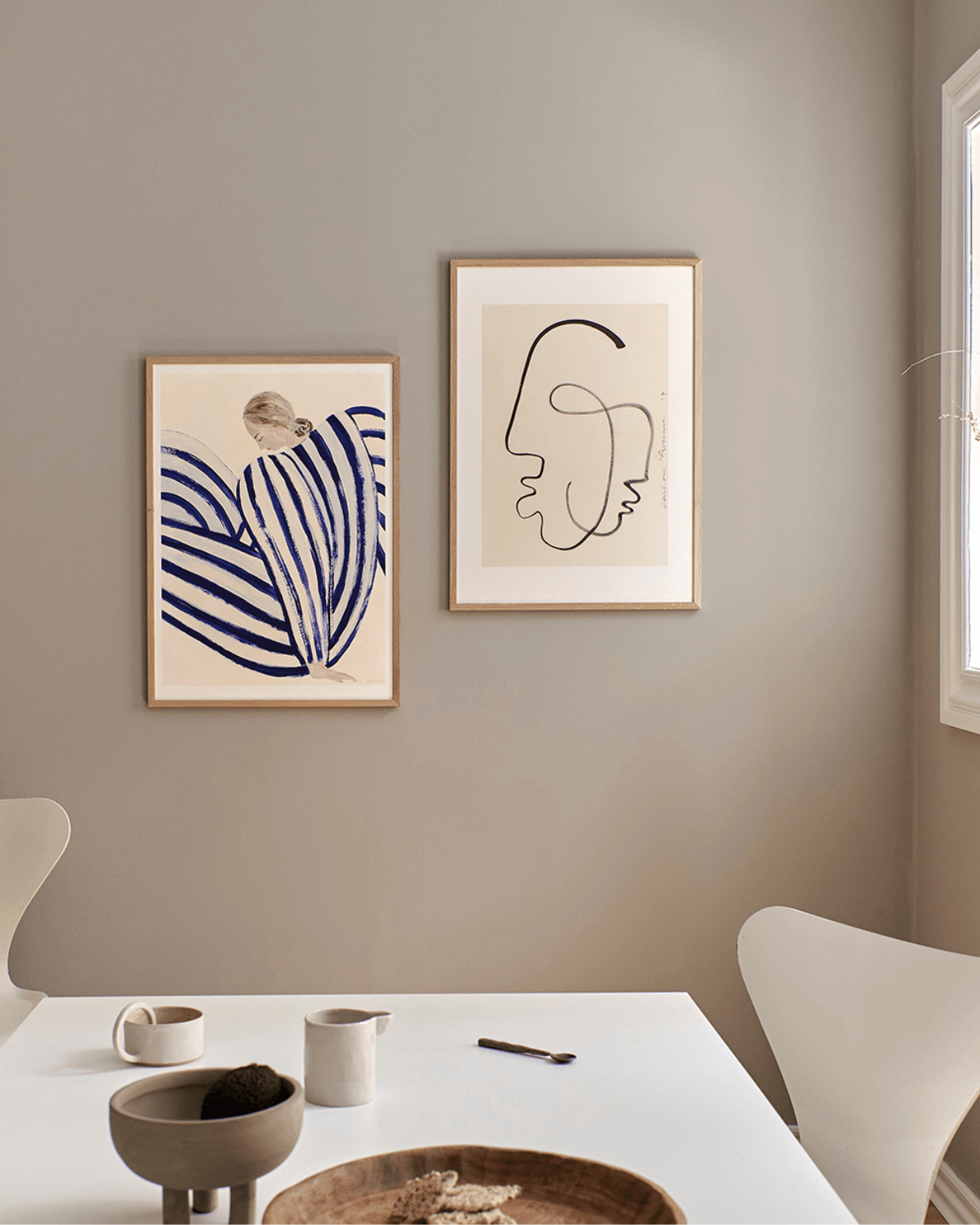 Smuk og rolig spisestue med grå beige vægge indrettet med kunsttryk fra the poster club, hvoraf det ene tryk er blue stripe at concorde af Sofia Lind. 