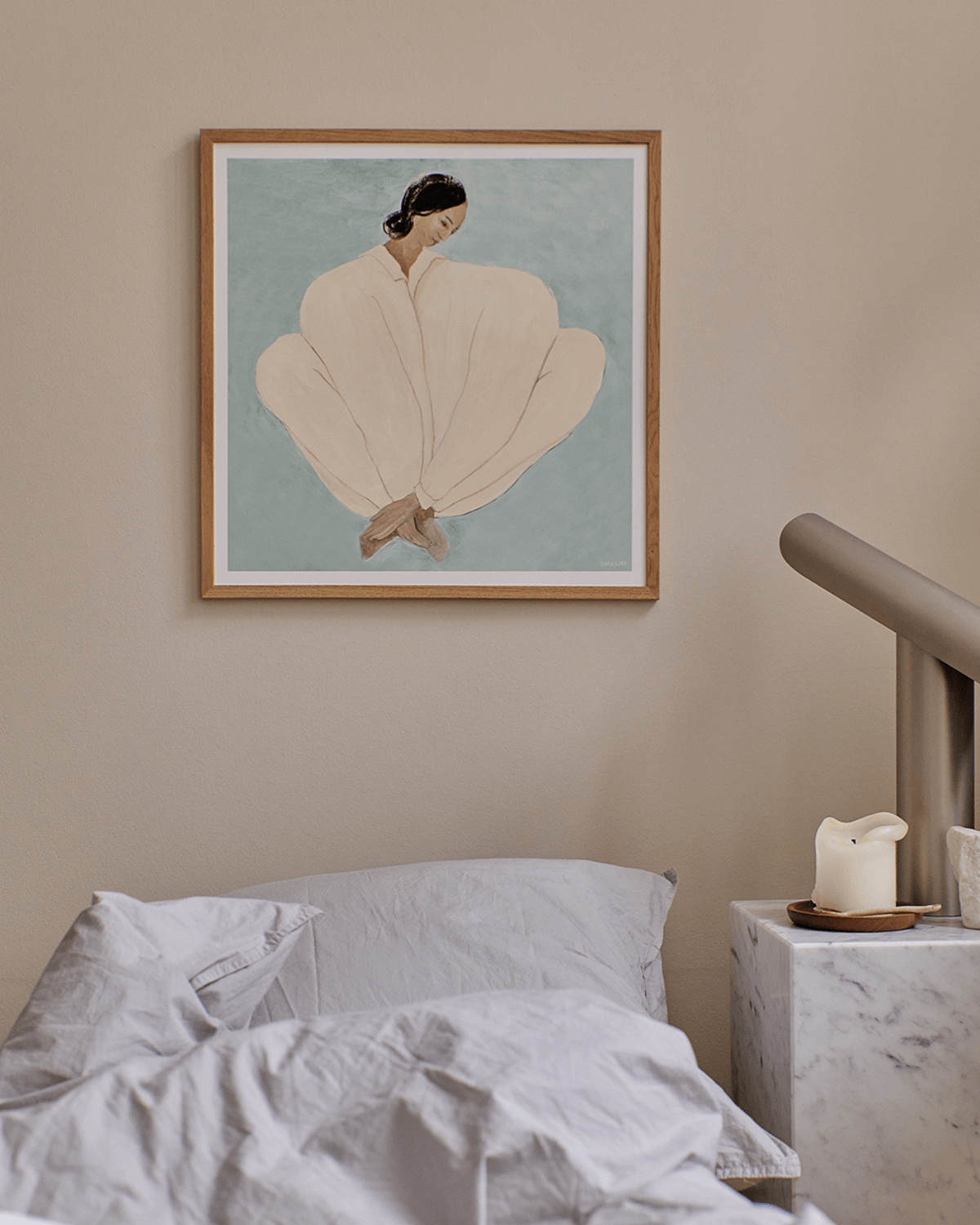 Kunsttryk med  kvinde i bløde cremefarver mod støvet blå baggrund, illustrativ plakat af Sofia Lind indrammet i træramme – moderne nordisk kunsttryk til soveværelse.