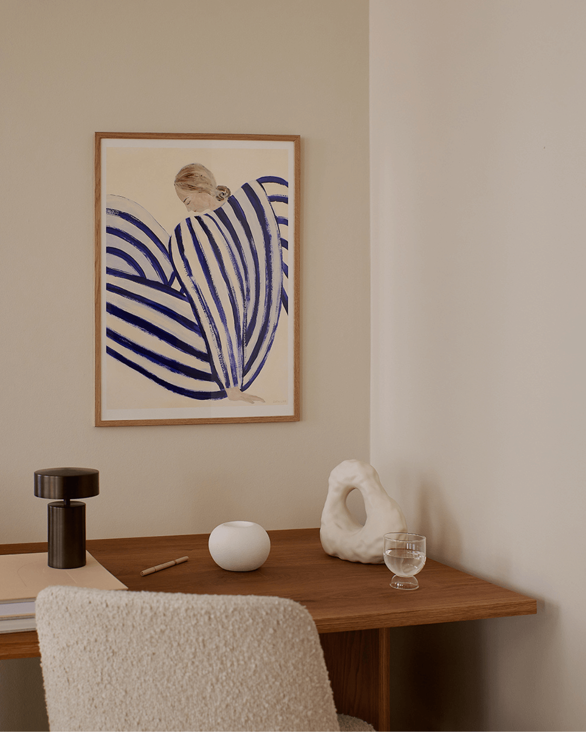 kunsttryk fra The Poster Club af en hvilende person i stribet tøj, set i profil mod en hvid baggrund, malet i en stiliseret form. indrammet og hængt på en beige væg på hjemmekontor. 