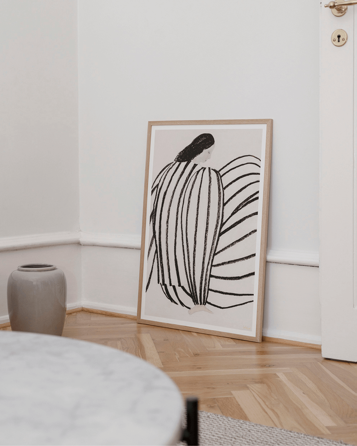 indrammet stilrent kunsttryk med kvinde i sort hvidt tøj, i smukt lyst hjem. 